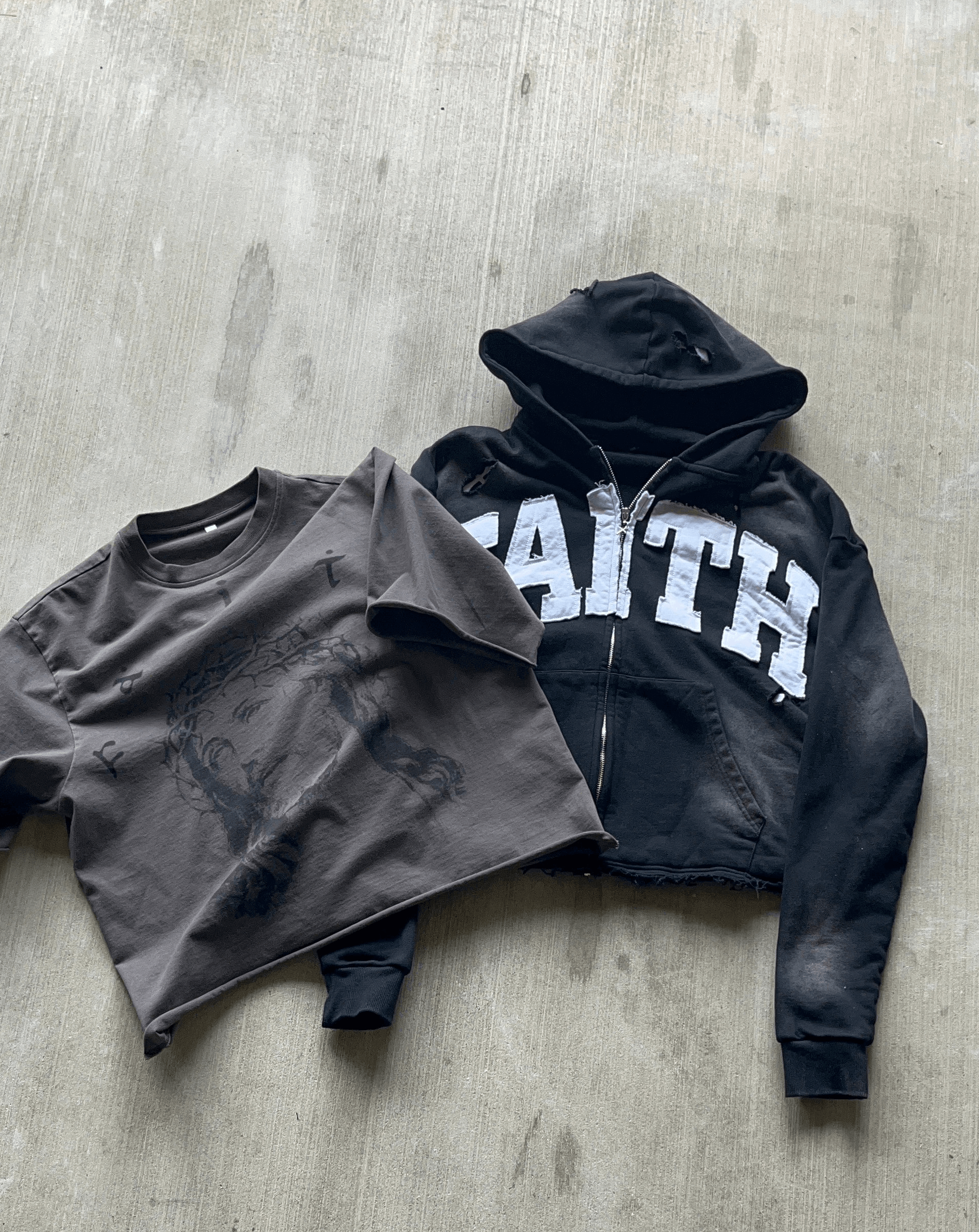 Men's black jersey crewneck and hoodie with "FAITH" print on a concrete background.